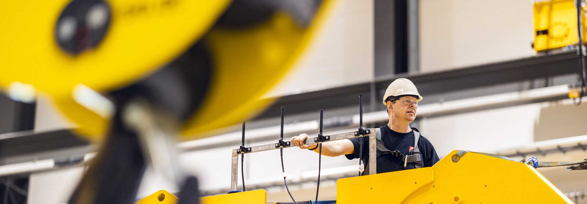 Person som er oppe på en stor, gul hydraulisk demper med sikkerhetsutstyr