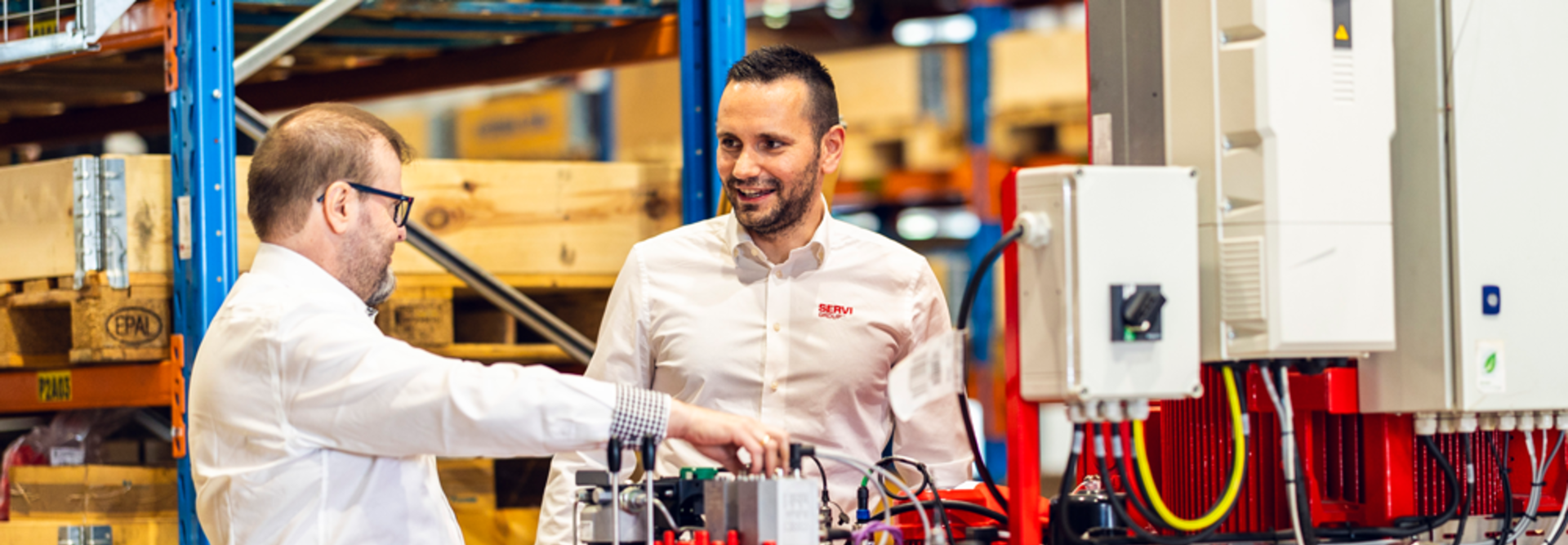 To selgere som snakker foran et hydraulikkaggregat