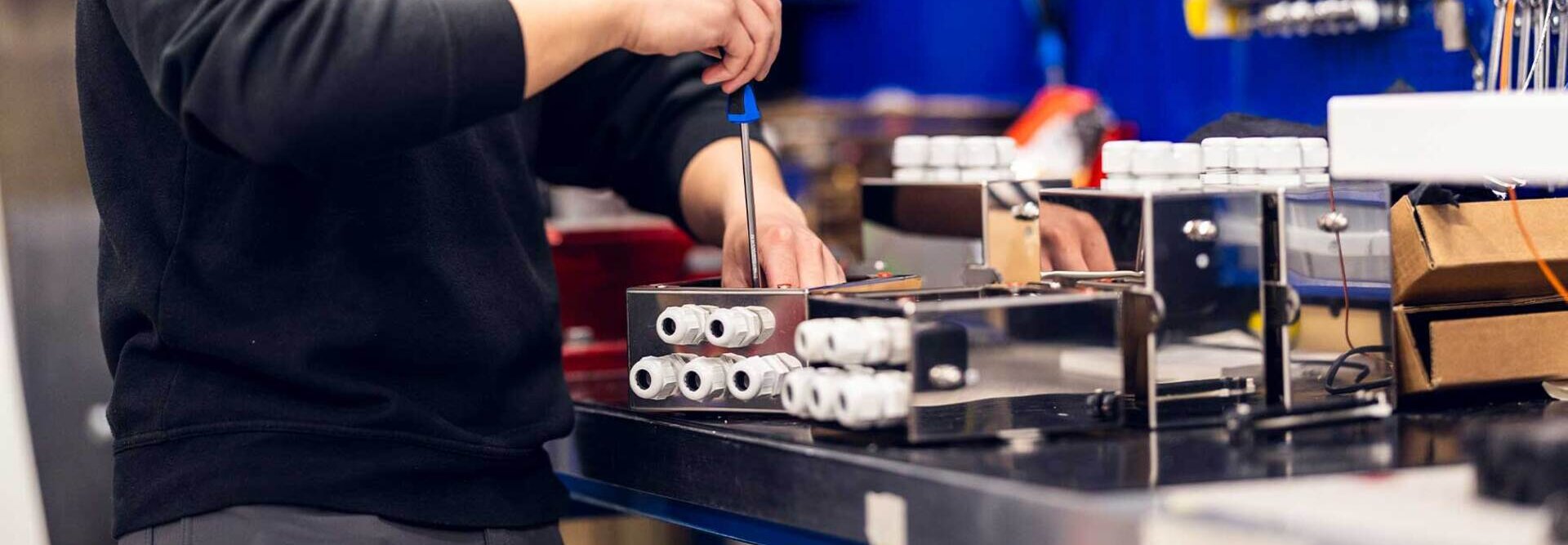 En tekniker fra Servi jobber fokusert med installasjon og finjustering av et elektro- og kontrollsystem i et industrielt miljø. | © Øyvind Welle