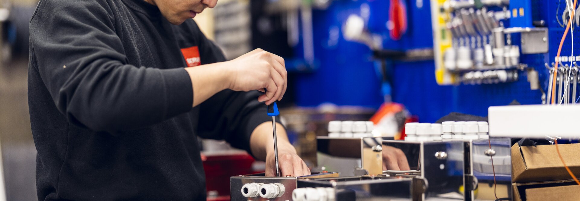 En tekniker fra Servi jobber fokusert med installasjon og finjustering av et elektro- og kontrollsystem i et industrielt miljø. | © Øyvind Welle