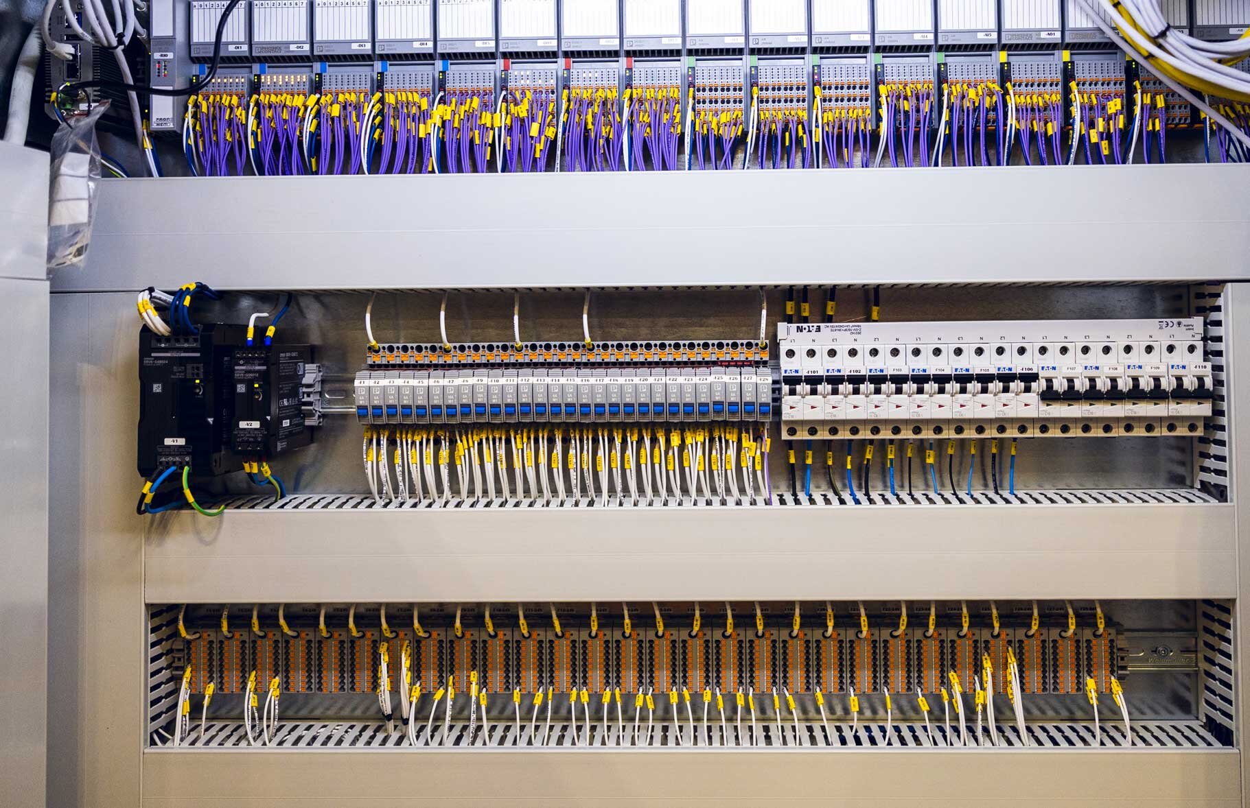 Innsiden av et større elektroskap fylt med elektriske komponenter, ledninger og koblinger | © Øyvind Welle