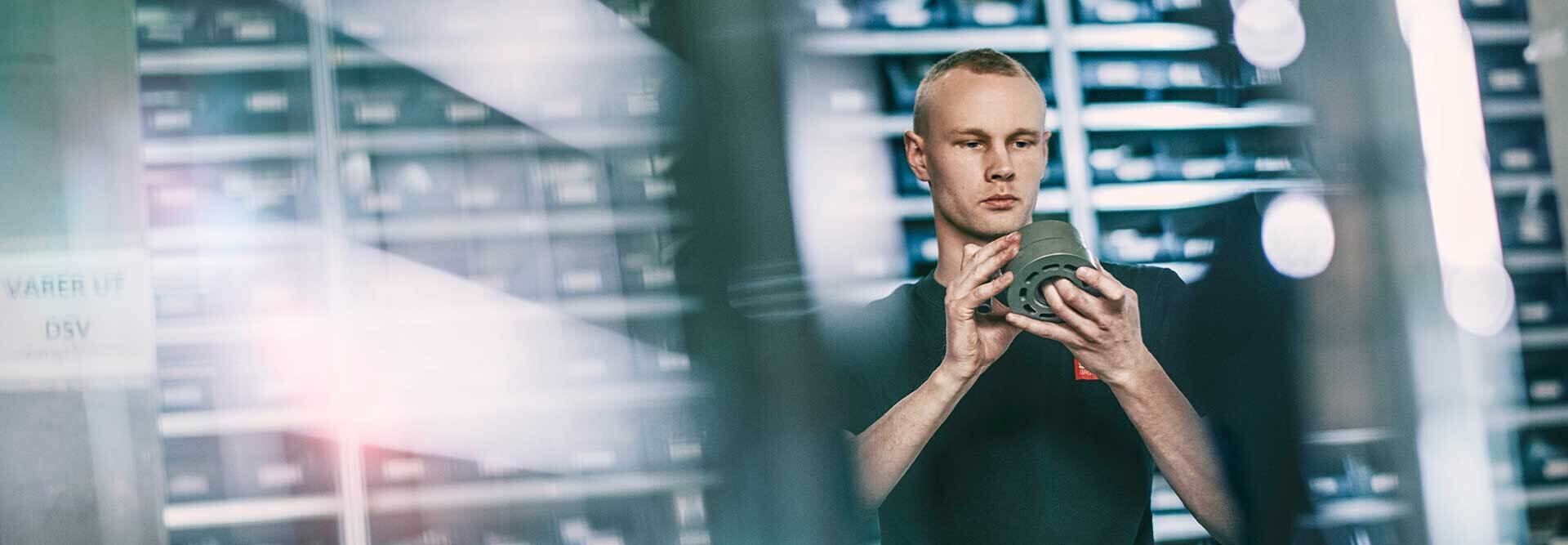 person ser på hydraulikk-komponent på lageret