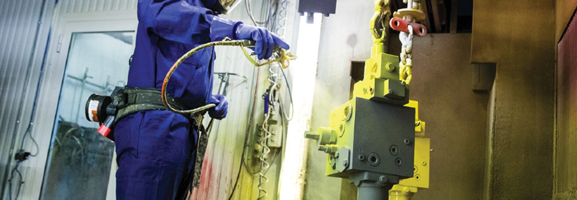 person overflatebehandler en hydraulikkblokk i gul farge