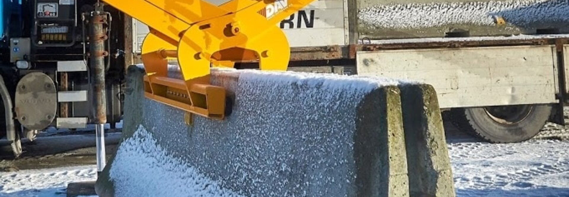  Et bilde av en autovern løfteteng fra BSV som løfter en stor betongblokk sett fra siden. Det er snø på bakken og rundt byggeplassen, og betongblokken henger i luften.
