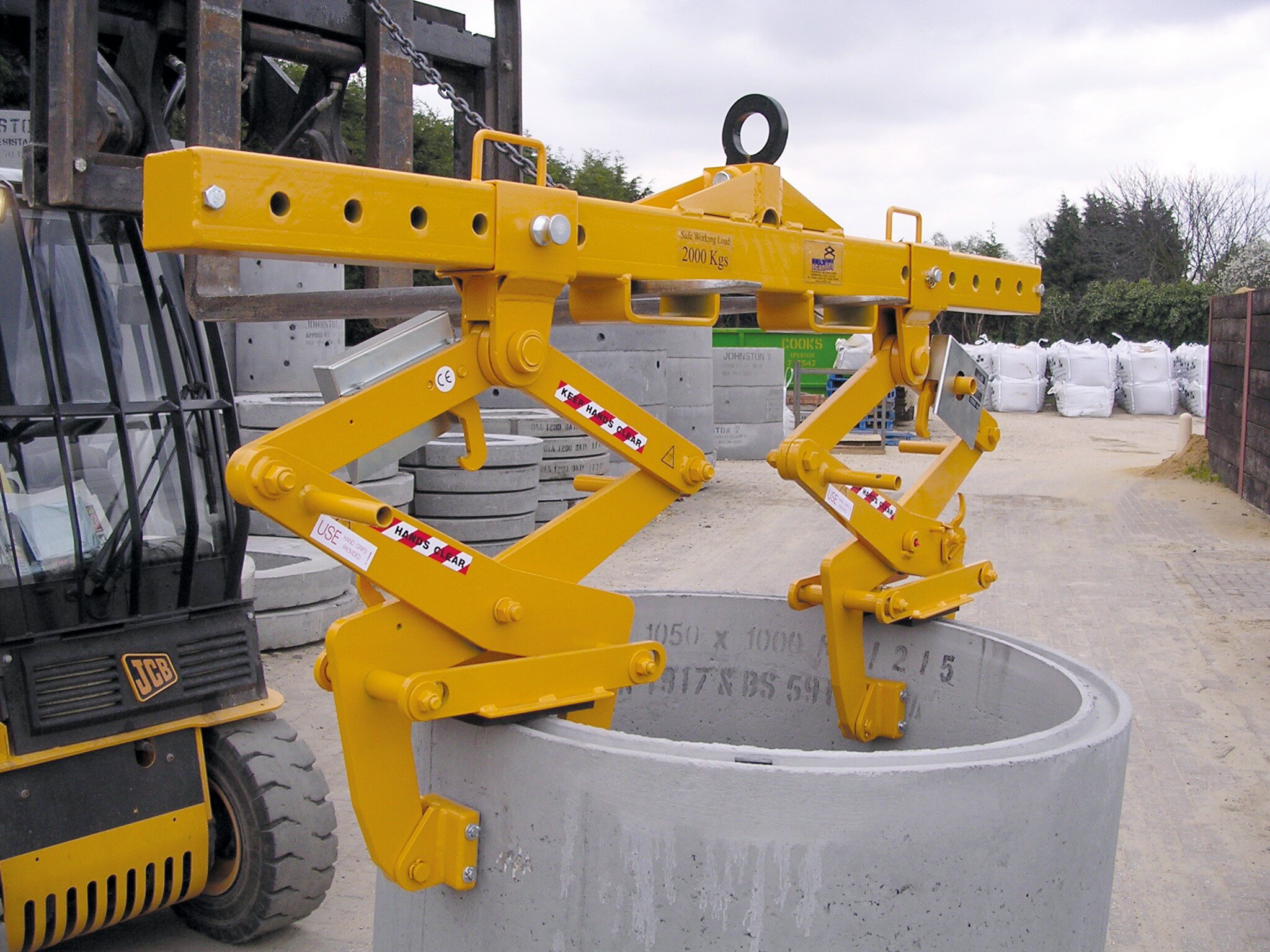 An image of a manhole ring lifting yoke from BSV in use at a construction site. The lifting yoke is lifting a large manhole ring, and the workers on site ensure the lift is performed safely and efficiently.