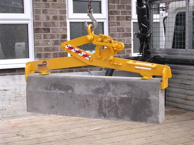 Et bilde av en mekanisk løftetang fra BSV som løfter et betongelement. Løftetangen er i bruk på en byggeplass, og betongelementet henger i luften.