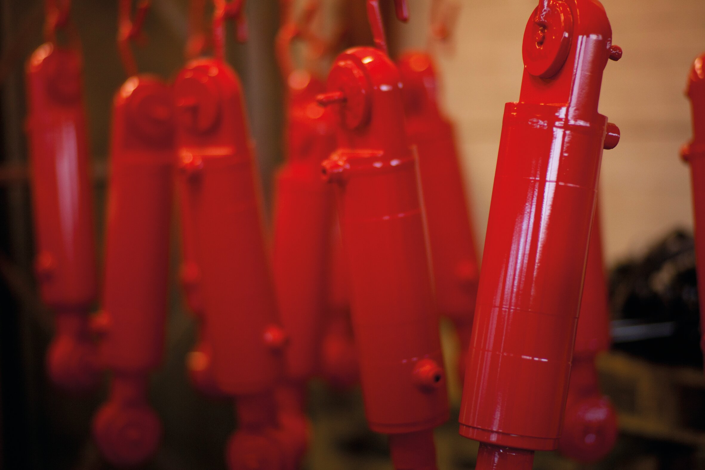 Red CD25 cylinders hanging after having been painted
