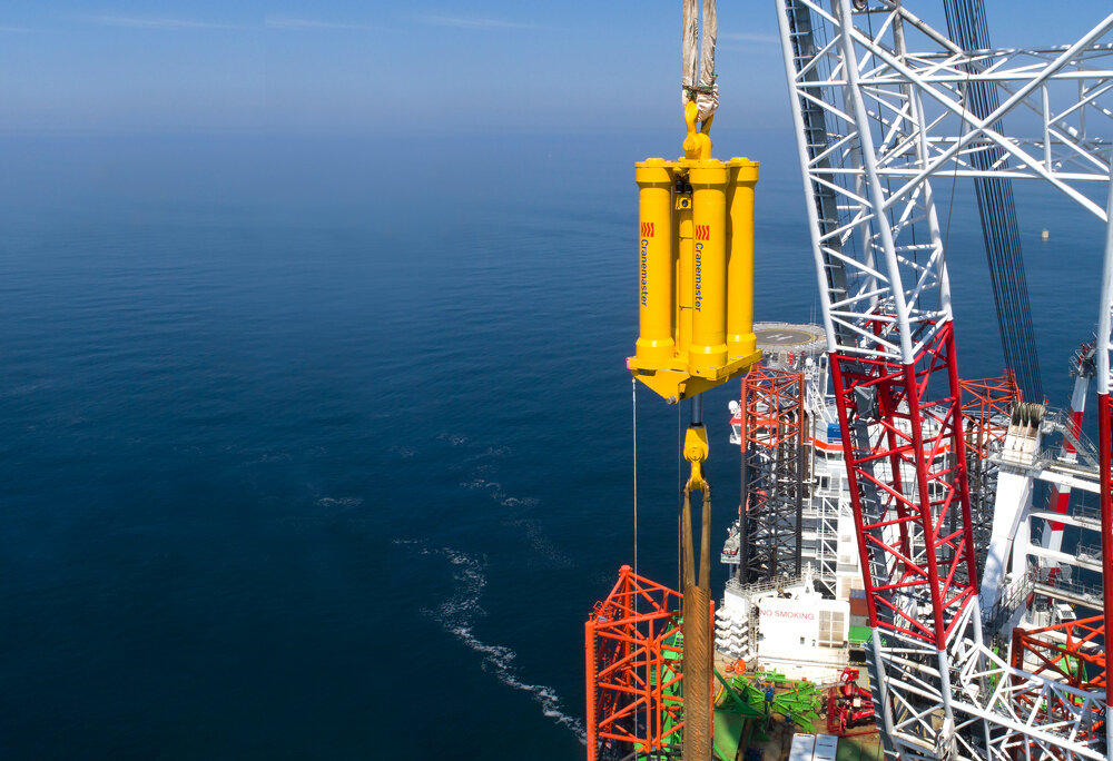 Yellow Cranemaster damper at sea hanging on a offshore wind rig