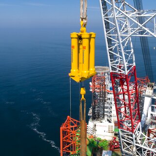 Yellow Cranemaster damper at sea hanging on a offshore wind rig