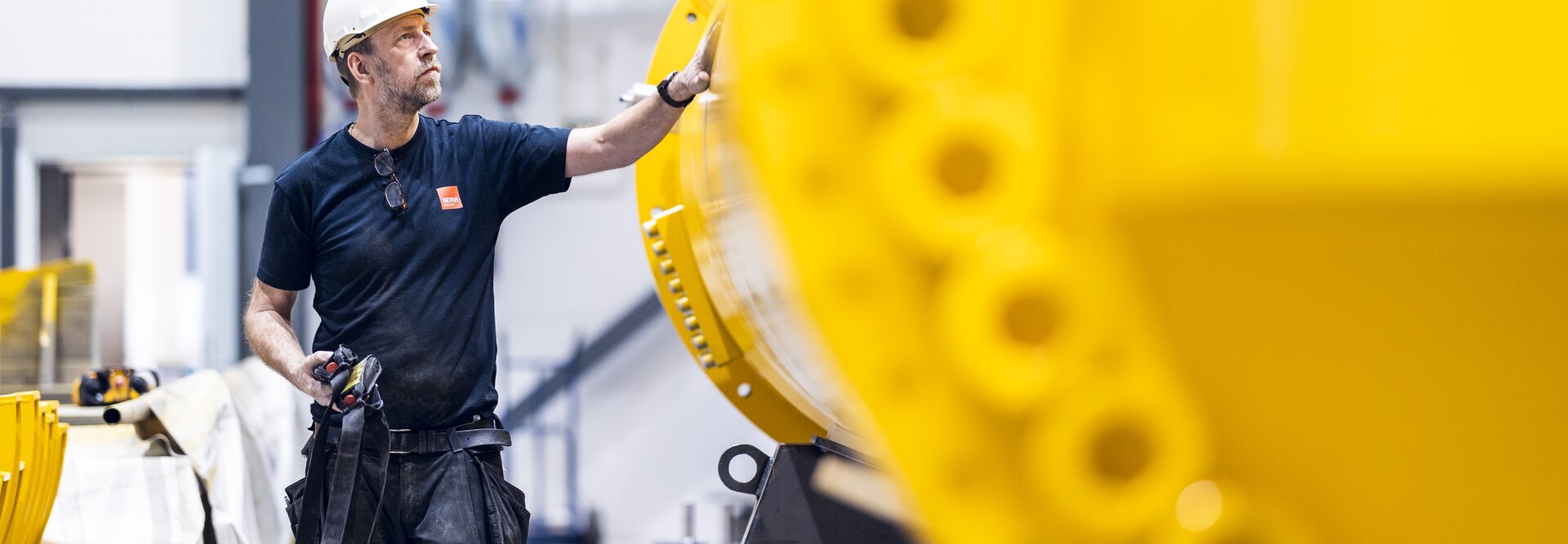 Produksjonsmedarbeider går ved siden av gul sylinder-reservedel til hydraulisk demper
