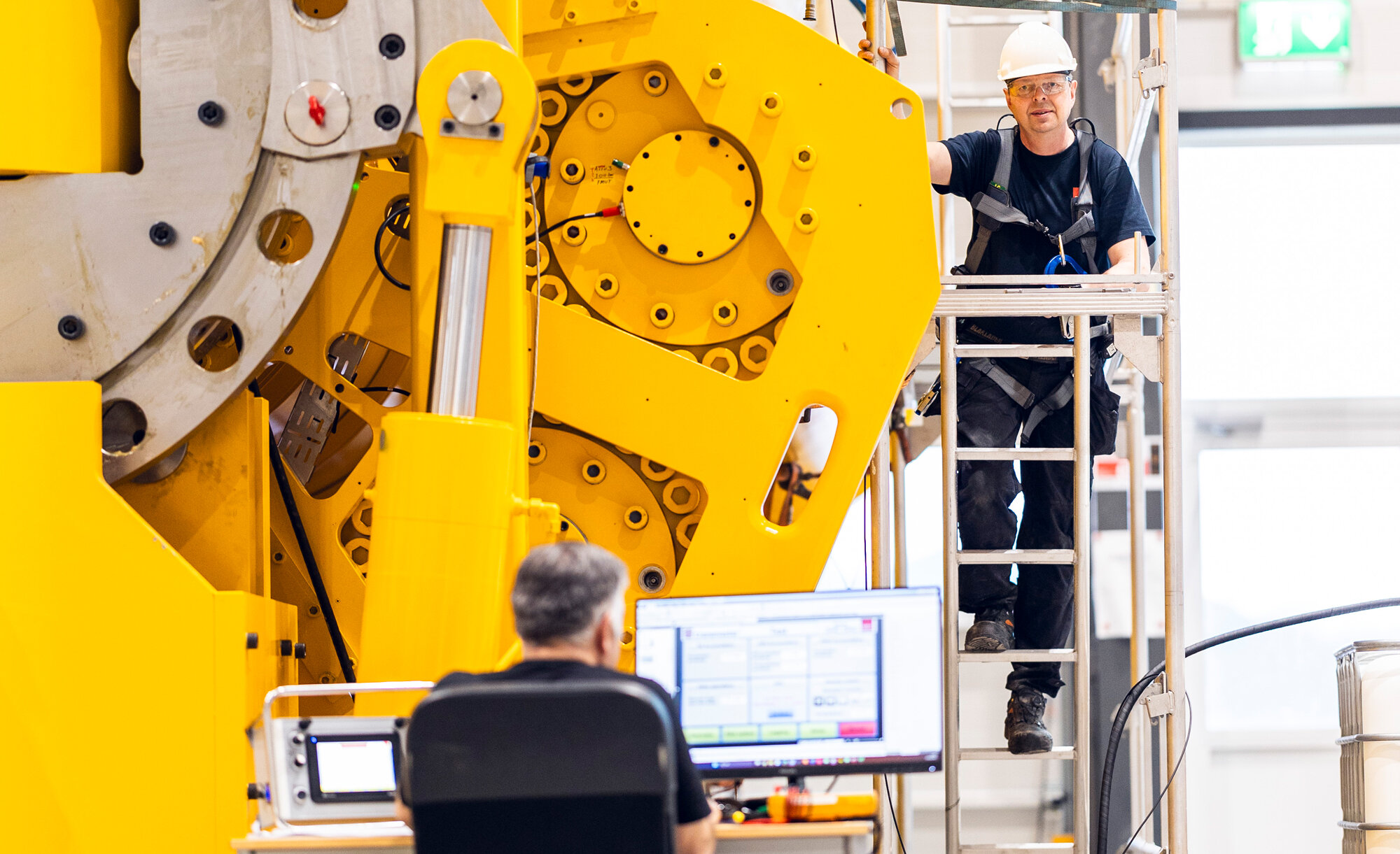 Two people working with hydraulic shock absorber in production hall