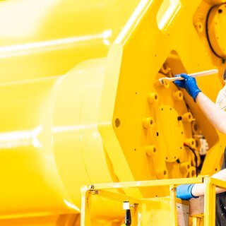 En person flekkmaler en stor hydraulisk demper