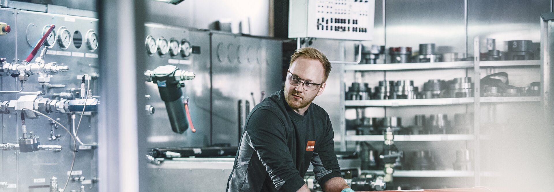 En person fikser akkumulator med flere hydrauliske komponenter i bakgrunnen