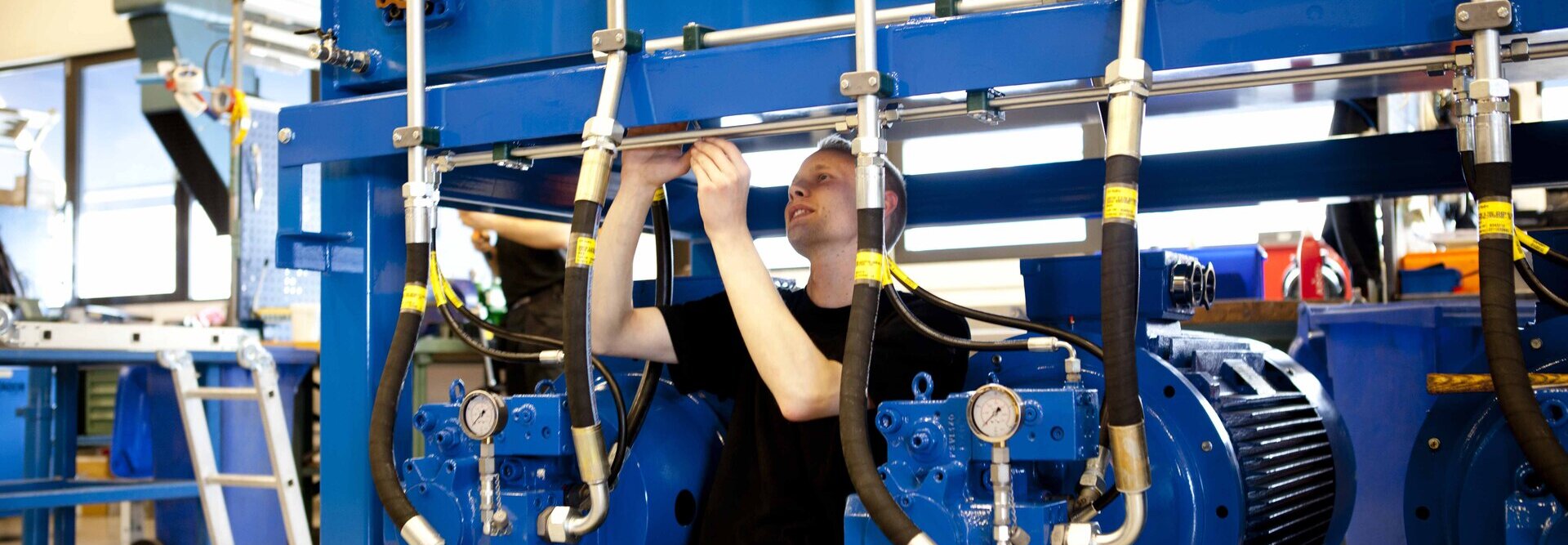 Person in workshop working on a blue hydraulic power unit