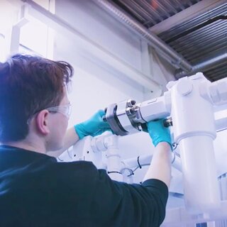 Person skrur på hydraulikkaggregat med grønne hansker