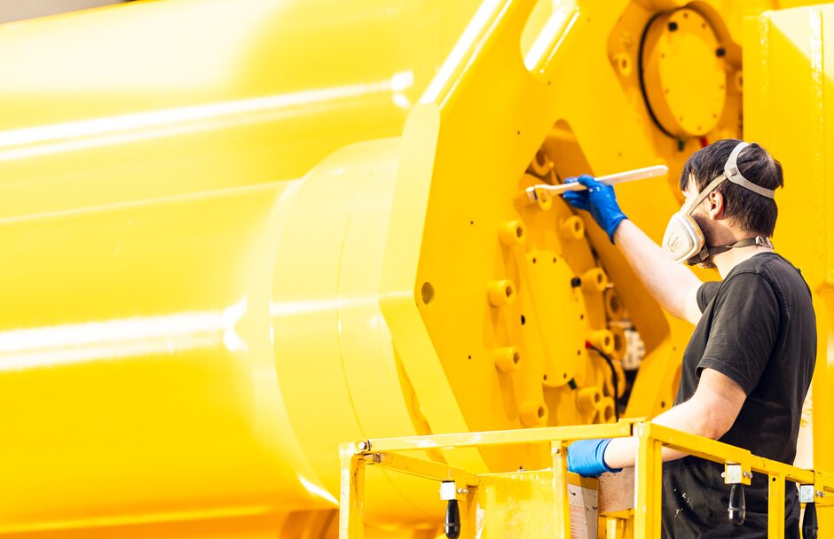 En person flekkmaler en stor hydraulisk demper